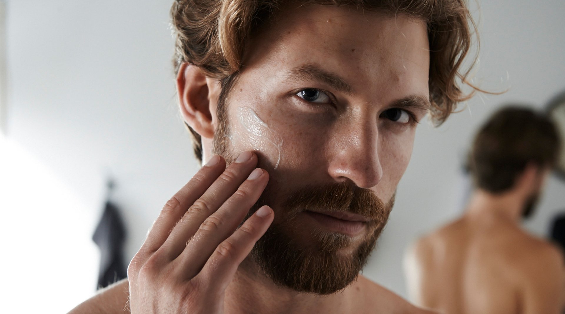 ann massiert Feuchtigkeitspflege in seinen frisch rasierten 5-Tage-Bart ein